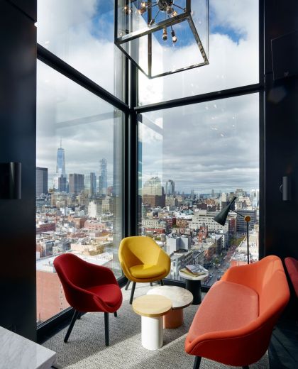 Colourful modern seating in corner of cloudM at citizenM New York Bowery bar with view of city skyline on a cloudy day