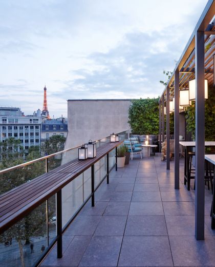Soirée sur la terrasse rooftop de cloudM Paris Champs-Élysées avec lanternes et tables en marbre blanc, la Tour Eiffel en fond
