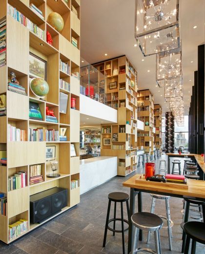 Binnen lichte en moderne cloudM Tower of London-bar met boeken en kunstwerken op rekken van vloer tot plafond