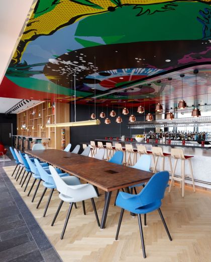 Long table and bar under colourful ceiling at cloudM rootop bar in Washington DC